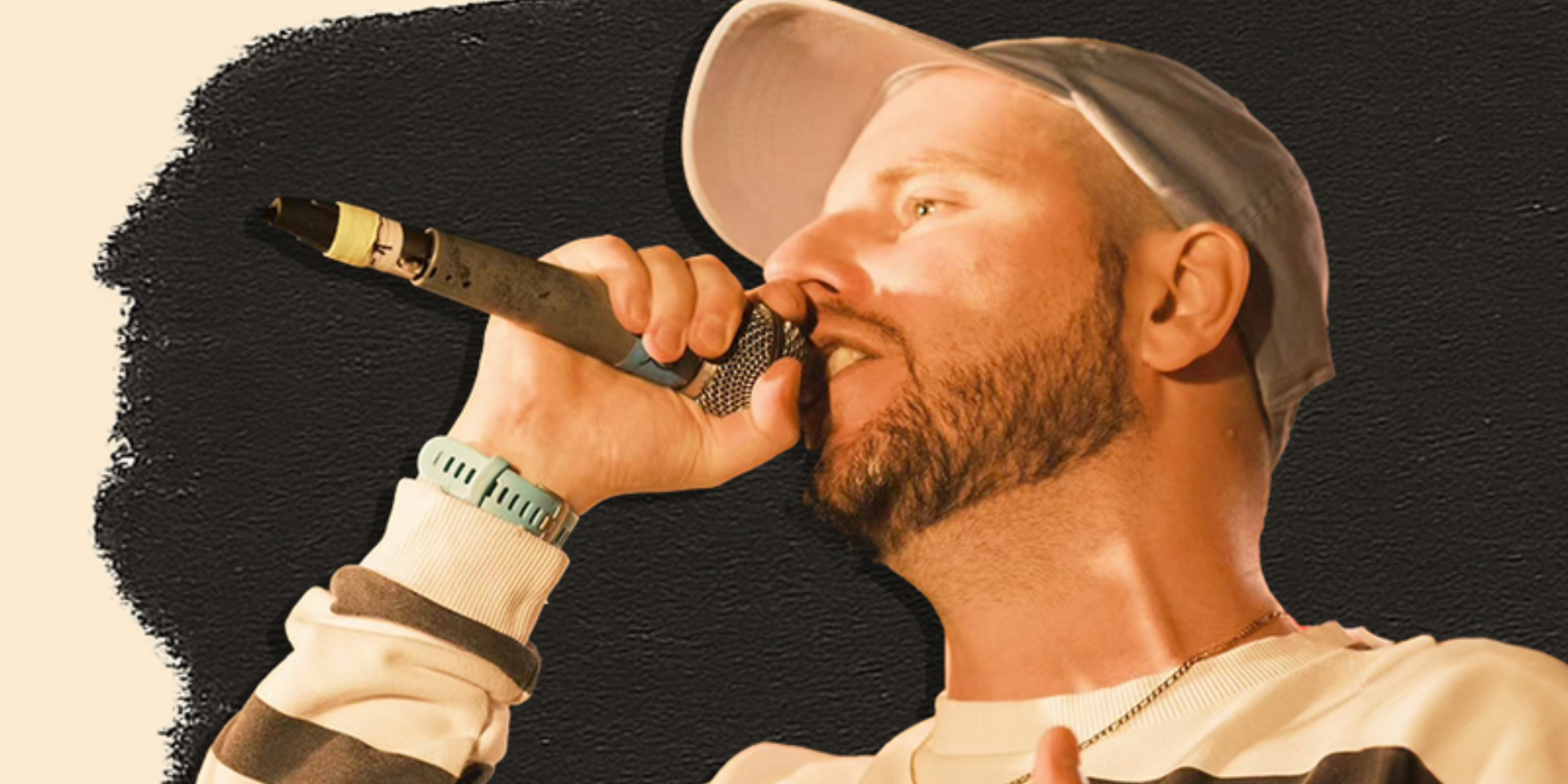 A white man with a red beard holds a mic to his mouth