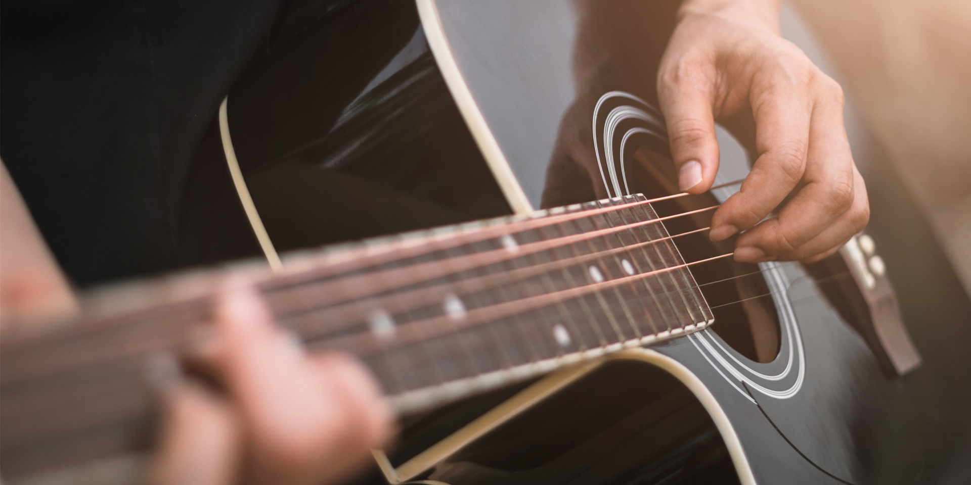 A hand playing a blue acoustic guitar