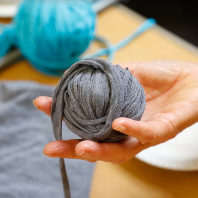 someone holding a grey ball of yarn